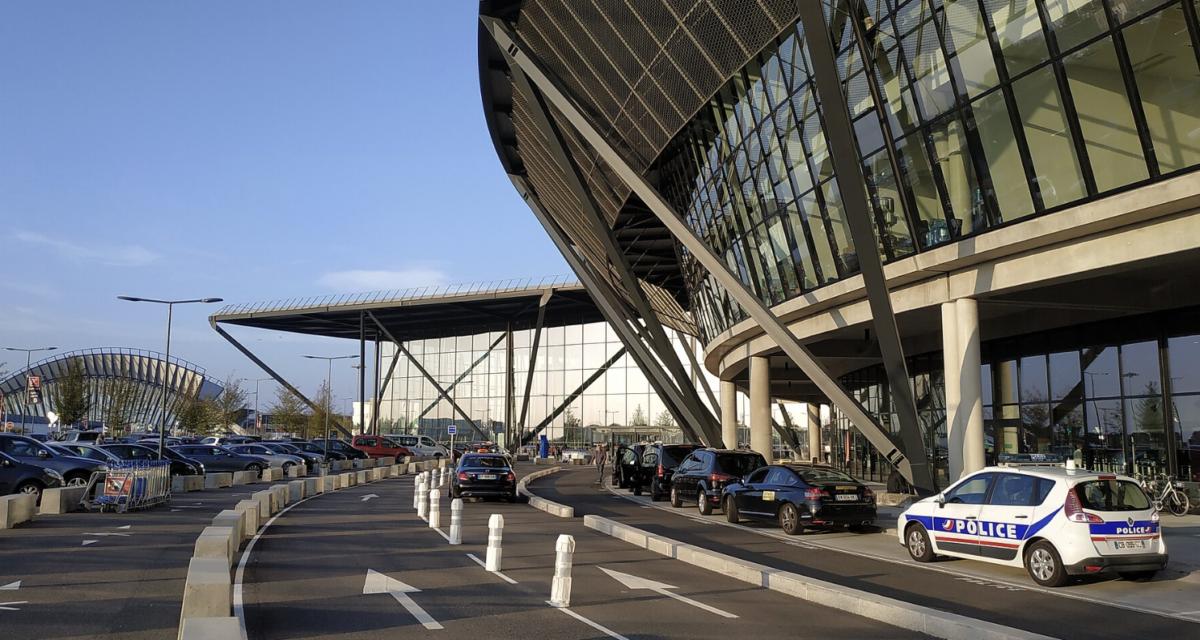 Robot autonome soulevant une voiture dans un parking d'aéroport automatisé