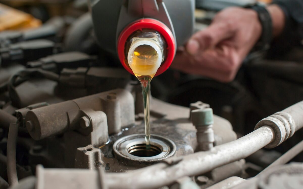 a man pours oil into a car engine close-up